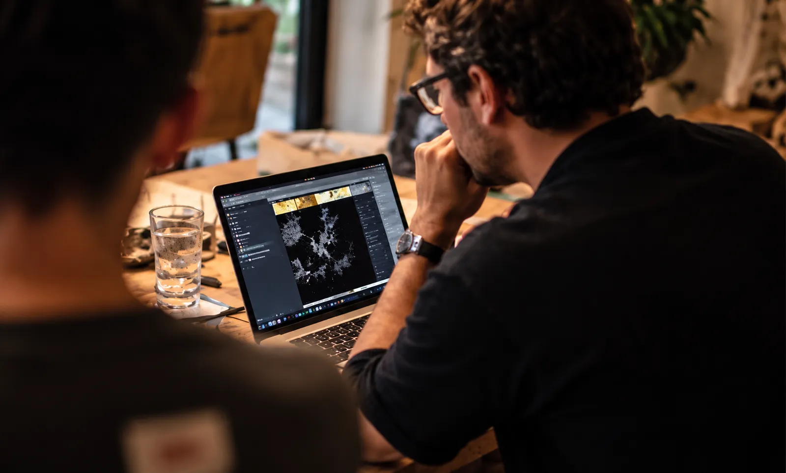 Twee deelnemers aan een houten tafel kijken samen naar een laptop